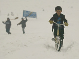 A Young Afghan Boy Rides His Bicycle on a Snow Covered Street Photographie