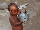 A Boy in a Slum Along the Yamuna River in the Older Part of New Delhi Drinks Water from a Tea Pot Photographic Print