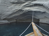 The Bow of a Boat on Smooth Water Below a Rocky Cliff Photographic Print