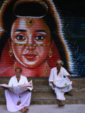 Local Men Read Newspapers in Front of Painted Shutter, Kozhikode, Kerala, India Photographic Print by Greg Elms