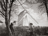 Men Chopping Wood Near a Windmill, 1920s Photographic Print