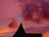 Brilliant Red and Burgundy Sunset Clouds Over a Thailand Roof Line Photographie par Jason Edwards