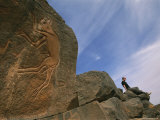 Woman Sits on Boulders Near Rocks with Animal Carvings Photographie par Bobby Model