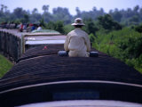 Man Sitting Alone on the Roof of a Carriage of the Battambang to Phnom Penh Train Fotografisk trykk av Andrew Burke Man Sitting Alone on the Roof of a Carriage of the Battambang to Phnom Penh Train Fotografisk trykk av Andrew Burke