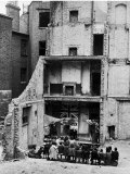 Hans Wild - Children in Aldgate Using the Ruins of a Bombed House as a Stage for a Vaudeville Show Speciální fotografická reprodukce Hans Wild - Children in Aldgate Using the Ruins of a Bombed House as a Stage for a Vaudeville Show Speciální fotografická reprodukce
