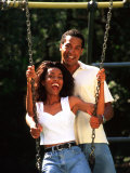 Middle-aged African-American Couple Playing on Swings in the Park Photographie par Bill Bachmann