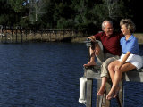 Healthy Couple Sitting on the Dock by a Lake Photographie par Bill Bachmann