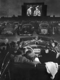 Young Couple Snuggling in Convertible as They Watch Large Screen Action at a Drive-In Movie Theater Lámina fotográfica por J. R. Eyerman