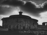 Round Stone Shaker Barn Dramatically Highlighted with Darkening Clouds Lámina fotográfica por John Loengard Round Stone Shaker Barn Dramatically Highlighted with Darkening Clouds Lámina fotográfica por John Loengard