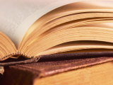 Open Book on Top of Pile of Old Books Photographic Print