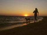 Woman and Her Dog Running Along Currituck Sound Beach at Sunset, Nags Head, North Carolina Photographie par Skip Brown