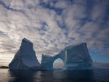 Large Iceberg with a Natural Arch, under a Cloud-Filled Sky, Antarctic Peninsula, Antarctica Photographic Print by Paul Nicklen