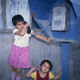 Two Small Uzbek Girls Using the Public Telephone in Bukhara, Uzbekistan, Central Asia Photographie par Christopher Rennie