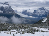 Rising fog and snow-dusted evergreens and mountains at Logan Pass Photographic Print by Michael Melford