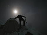 A mountain climber shakes snow from a tent on Nanga Parbat Photographic Print by Tommy Heinrich