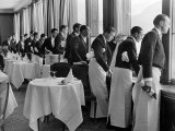 Waiters in the Grand Hotel Dining Room Lined Up at Window Watching Sonia Henie Ice Skating Outside Fotoprint van Alfred Eisenstaedt Waiters in the Grand Hotel Dining Room Lined Up at Window Watching Sonia Henie Ice Skating Outside Fotoprint van Alfred Eisenstaedt