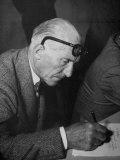 Swiss Architect Le Corbusier Leaning Down to Write with His Glasses Pushed Back on His Forehead Lámina fotográfica Swiss Architect Le Corbusier Leaning Down to Write with His Glasses Pushed Back on His Forehead Lámina fotográfica