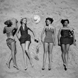 Four Models Showing Off the Latest Bathing Suit Fashions While Lying on a Sandy Florida Beach Fotografisk tryk af Nina Leen