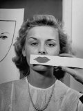 Young Girl Trying to Determine Which Lipstick Color Will Look Right with Her Complextion Lámina fotográfica por Nina Leen