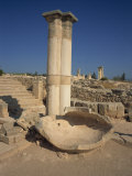 Stone Pithos in the Palaestra with Temple of Apollo in the Ruins of Kourion, South Cyprus Photographic Print by Teegan Tom