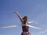 Female Runner Victorious at the Finish Line in a Track Race Lámina fotográfica