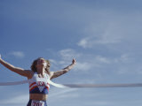 Female Runner Victorious at the Finish Line in a Track Race Lámina fotográfica