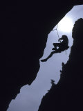 Silhouette of Rock Climber Hanging from Cliff Face Lámina fotográfica