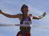 Male Runner Victorious at the Finish Line in a Track Race Lámina fotográfica