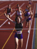 Female Runner Victorious at the Finish Line in a Track Race Lámina fotográfica