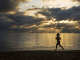 Silhouetted Woman Jogging on a Beach at Twilight Photographic Print by Mattias Klum