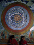 Two Young Buddhist Monks Seated under an Ornate Painting Photographie par Paul Chesley