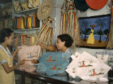 Shopkeeper at an Arts Co-Op Shows a Customer Embroidered Linens Photographic Print by Edwin L. Wisherd