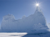 Sun Shines over the Peak of an Iceberg Frozen into the Ice Photographic Print by John Dunn