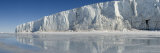 Three Skiers Pull Sleds on Sea Ice Near a Floating Glacier Tongue Photographic Print by John Dunn