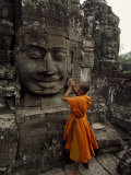 Young Buddhist Monk Prays at a Relief Statue of Buddha Lámina fotográfica por Paul Chesley