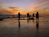 Children Playing on the Beach at Sunset with Family in the Background Photographie par James Forte