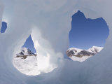 Mountain Peaks on Coburg Island Seen Through Holes in a Piece of Ice Photographic Print by John Dunn