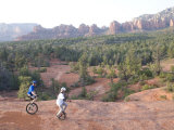 Two Men on Unicycles Ride a Rocky Ridge in the Arizona Desert Photographie par Skip Brown