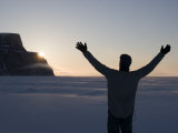 Man Standing on Frozen Ocean Welcoming the Sunrise with Open Arms Photographic Print by John Dunn