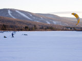 Man Tows Two Young Boys Behind a Kite across a Frozen Lake Photographie par Skip Brown