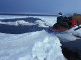Man on a Snowmobile Jumping an Water-Filled Crack in the Ice Photographie par Paul Nicklen
