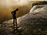 Swimmer Stands at the Lip of a Hidden Pool at Victoria Falls Fotografisk trykk av Annie Griffiths Belt