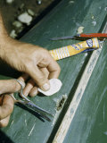 Man Mends a Hole in a Canvas Canoe with a Patch and Cement Photographie par Walter Meayers Edwards