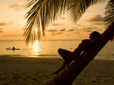Woman Resting on a Palm Tree at Sunset, Sunset over the Caribbean Sea Photographic Print by Richard Nowitz
