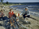 People Cook Frankfurters over a Campfire on a Lakeside Beach Fotografisk trykk av Andrew Brown People Cook Frankfurters over a Campfire on a Lakeside Beach Fotografisk trykk av Andrew Brown