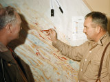 Man Points to a Map on Which Red Indicates Iron Deposits Fotografisk trykk av Andrew Brown Man Points to a Map on Which Red Indicates Iron Deposits Fotografisk trykk av Andrew Brown