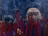 Chinese Man Lighting Incense at a Buddhist Temple Photographie par Jodi Cobb