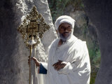 Old Ethiopian Orthodox Priest Holds a Large Brass Coptic Cross at Rock-Hewn Church of Adadi Maryam Photographie par Nigel Pavitt