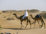 Bedu Rides His Camel Amongst the Sand Dunes in the Desert Photographic Print by John Warburton-lee