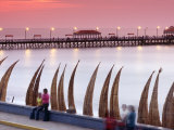 Waterfront Scene at Huanchaco in Peru, Locals Relax Next to Totora Boats Stacked Along the Beach Fotografie-Druck von Andrew Watson